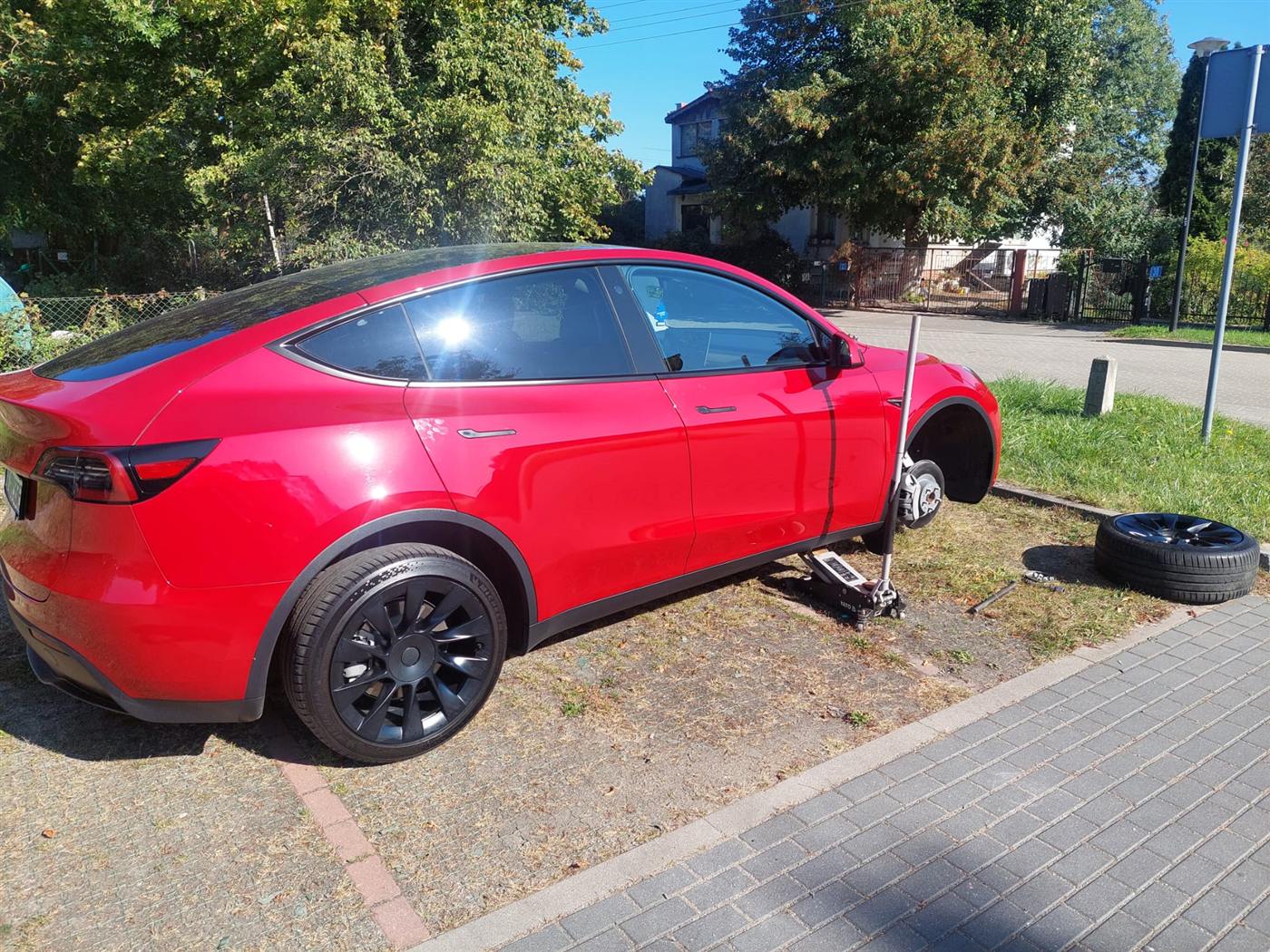 Wymiana koła w Tesli na miejscu, auto na podnośniku